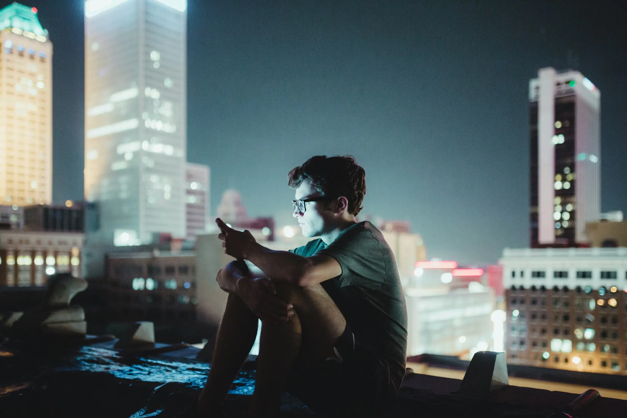 Someone on their phone on a city rooftop at night